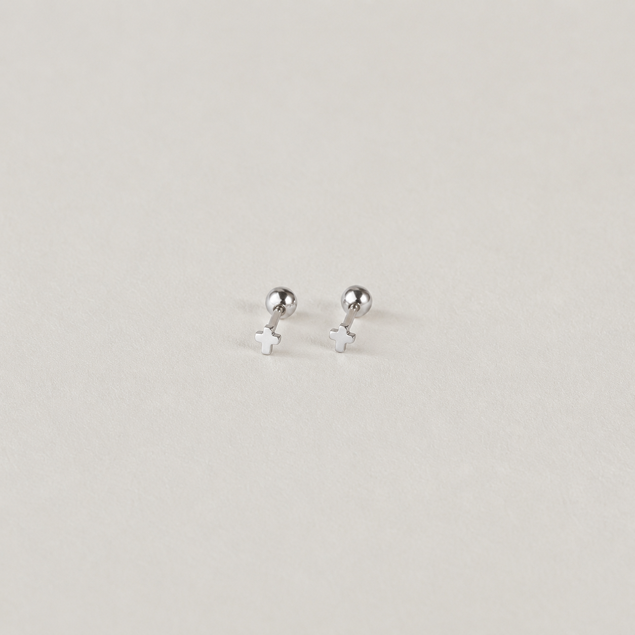 Pair of silver stud earrings on a light gray background